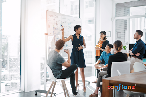 A group of people in a meeting room with a whiteboard, discussing Odoo Integration.